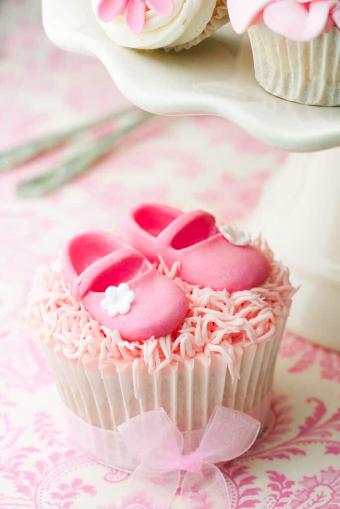 pink cupcake with baby shoes on top